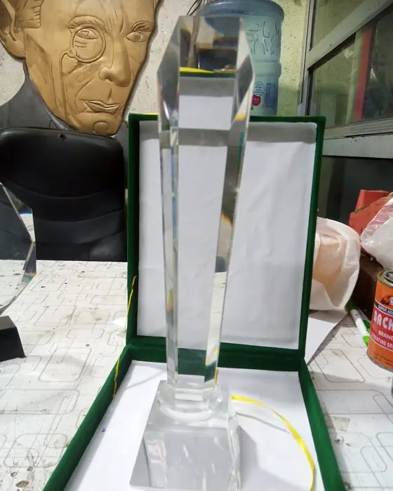 A tall crystal trophy standing in a green presentation box